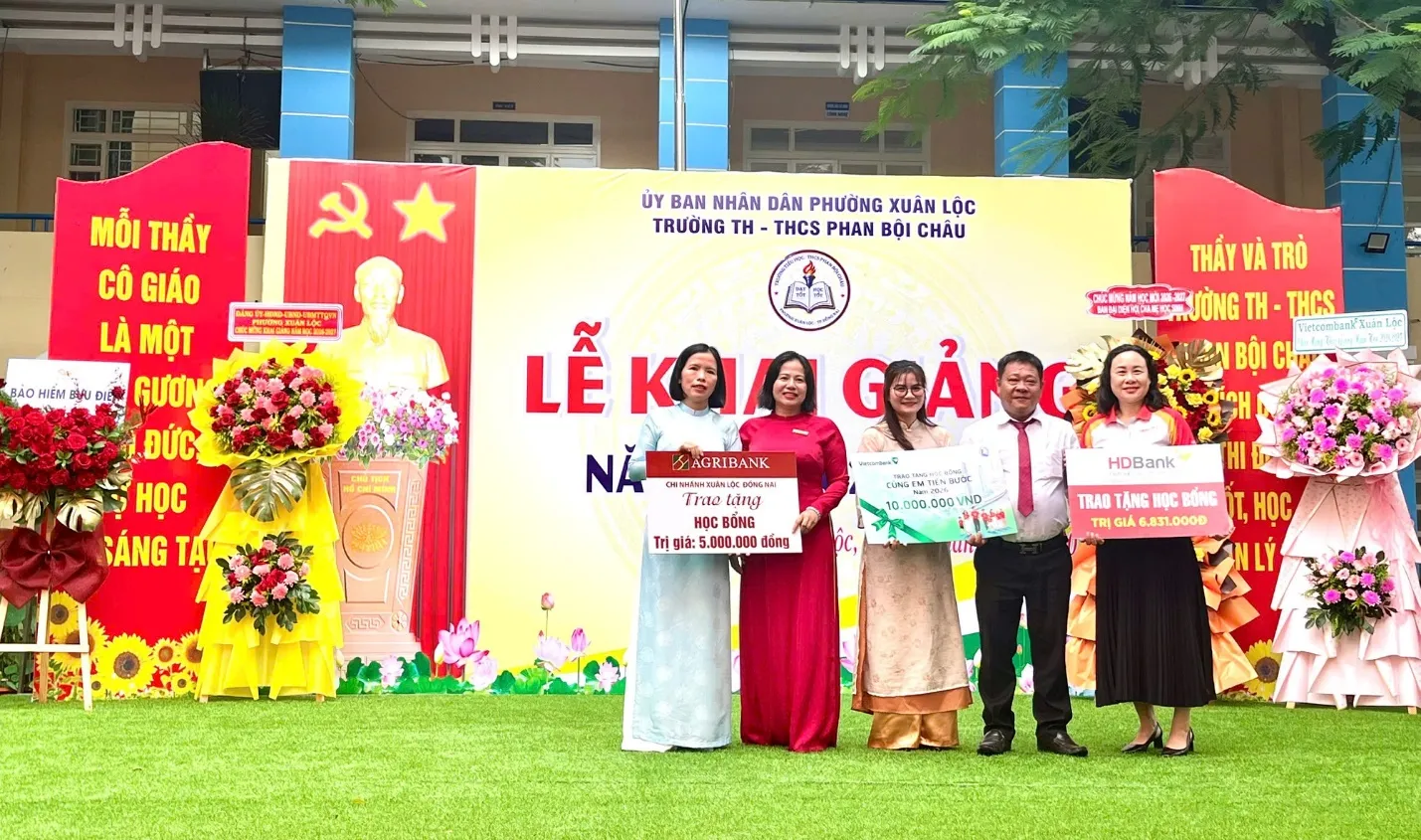 Đại diện các mạnh thường quân trao tặng bảng tượng trưng học bổng cho các em học sinh có hoàn cảnh khó khan